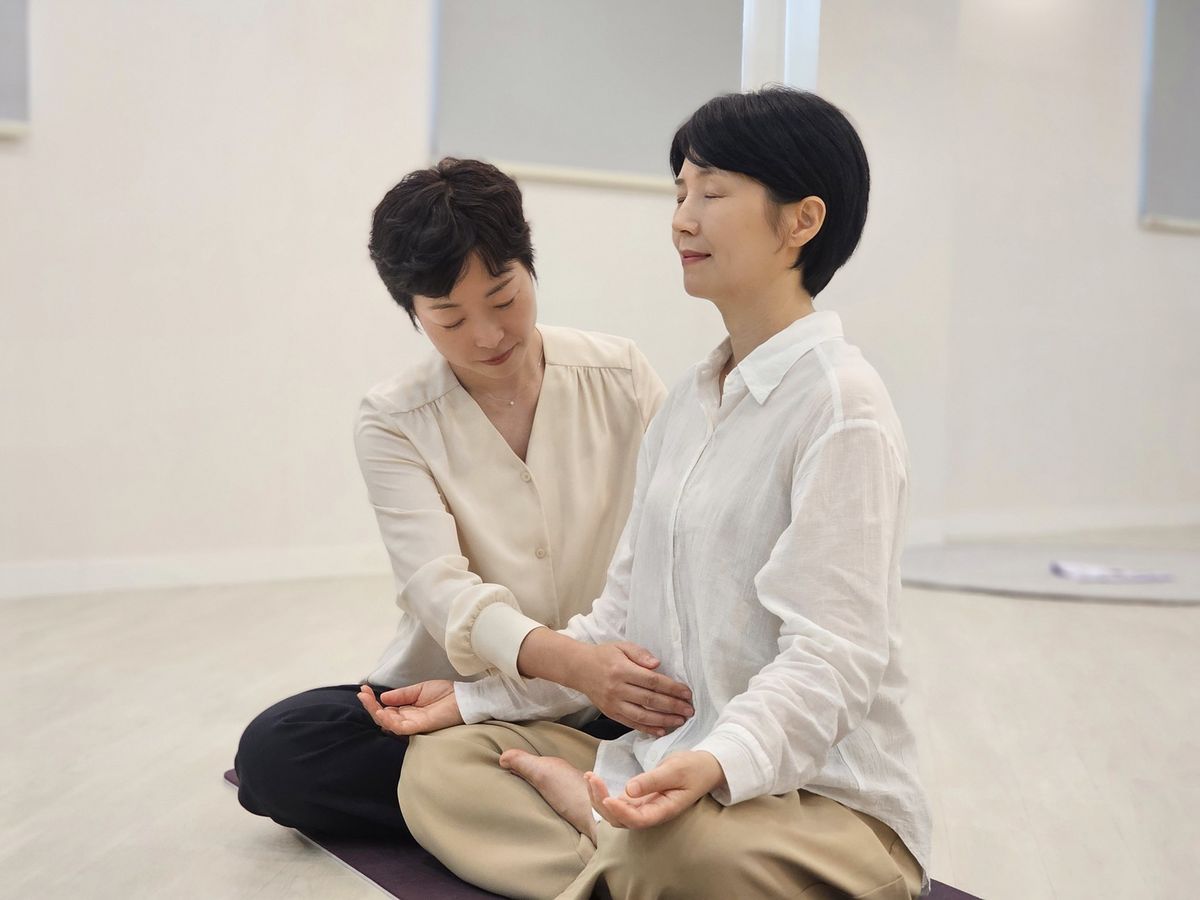 트레이너가 회원의 호흡 자세를 잡아주는 브레인 호흡 장면